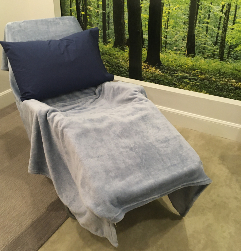 Room 4 with Reflexology chair in place Reflexology chair with a fluffy blanket and a cushion, against a backdrop of a forest scene on the wall